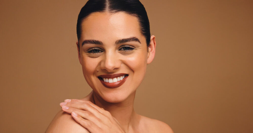 Beauty, happy and portrait of woman in studio for cosmetics, transformation and makeup. Mockup space, salon and person with confidence, facial glow and aesthetic for skincare on brown background.